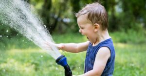 boy playing in the yard with a hose